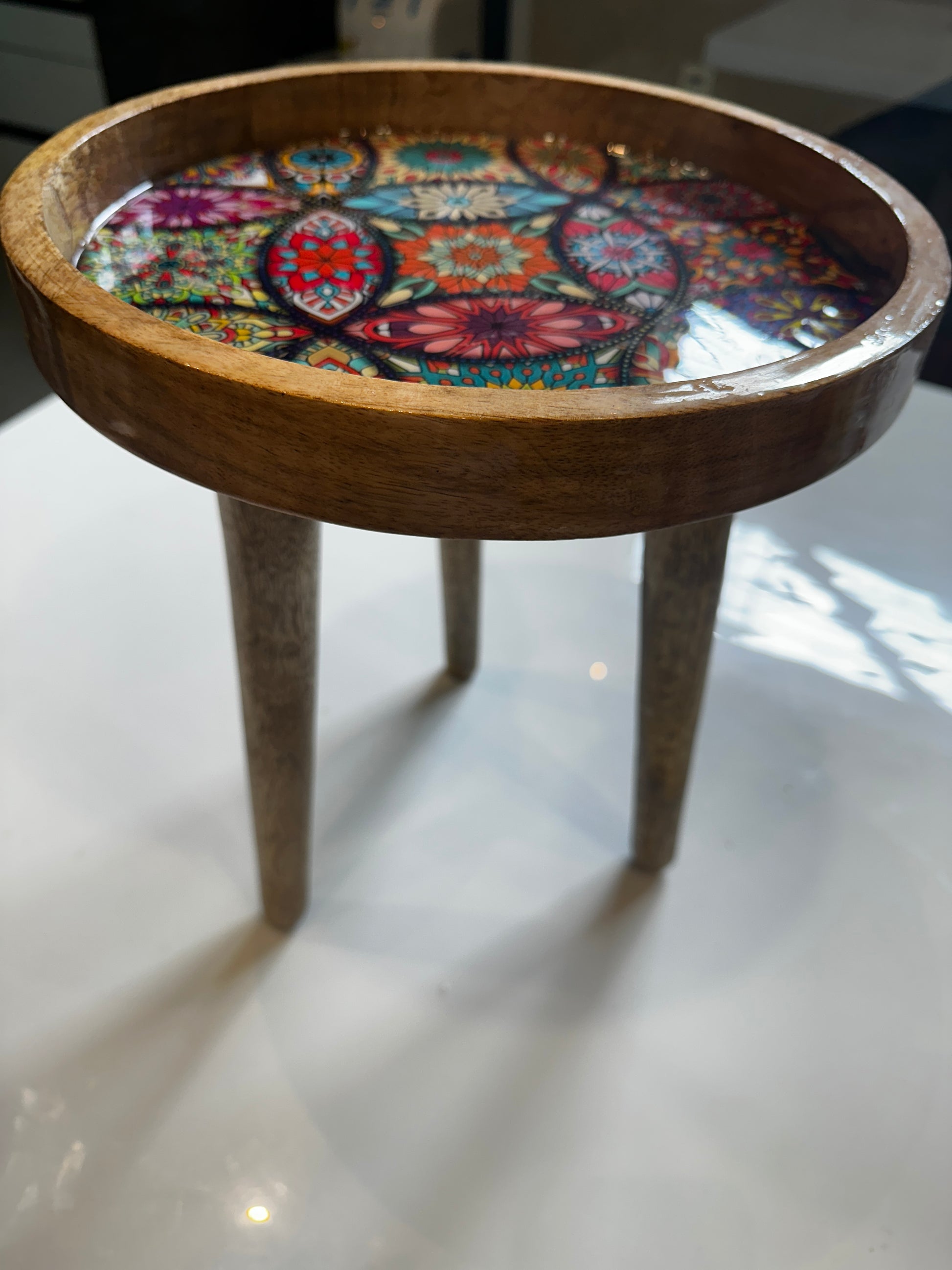 Wooden stool with a colorful mosaic pattern on a white surface